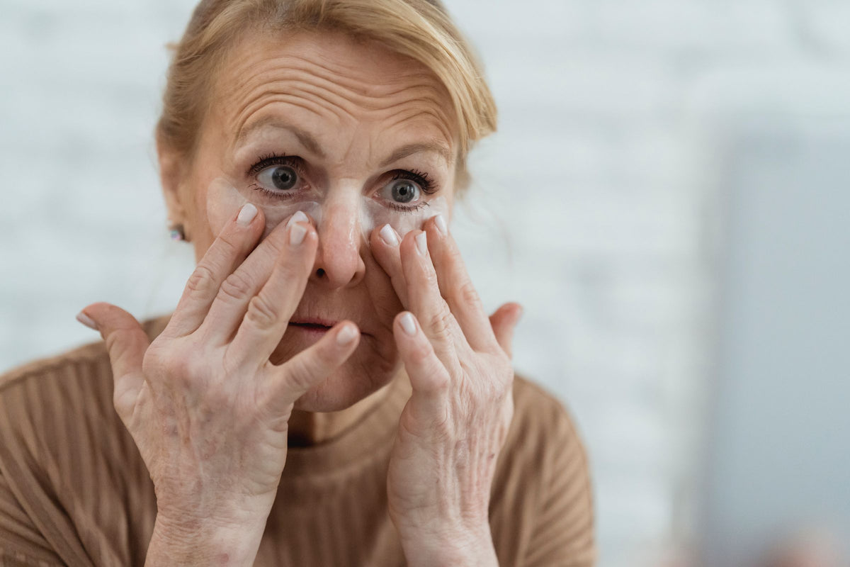 Aplicação delicada de um cuidado facial junto ao espelho.